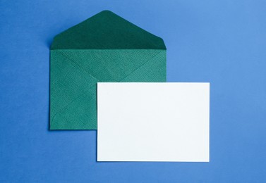 Photo of Blank invitation card and envelope on blue background, top view. Space for design