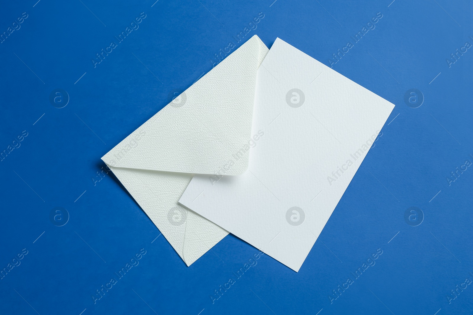 Blank invitation card and envelope on blue background, top view. Space for design Photo of Blank invitation card and envelope on blue background, top view. Space for design