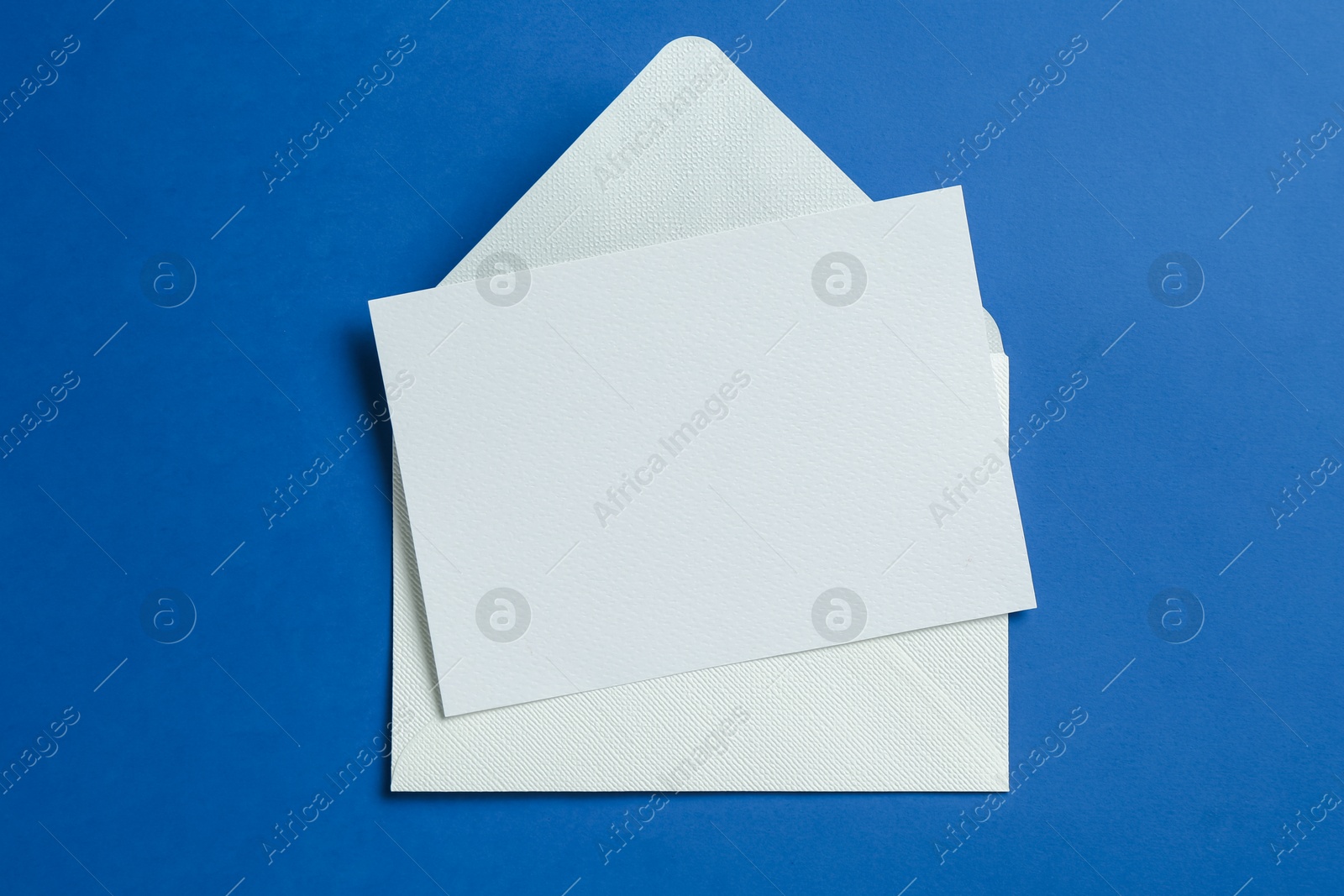Blank invitation card and envelope on blue background, top view. Space for design Photo of Blank invitation card and envelope on blue background, top view. Space for design