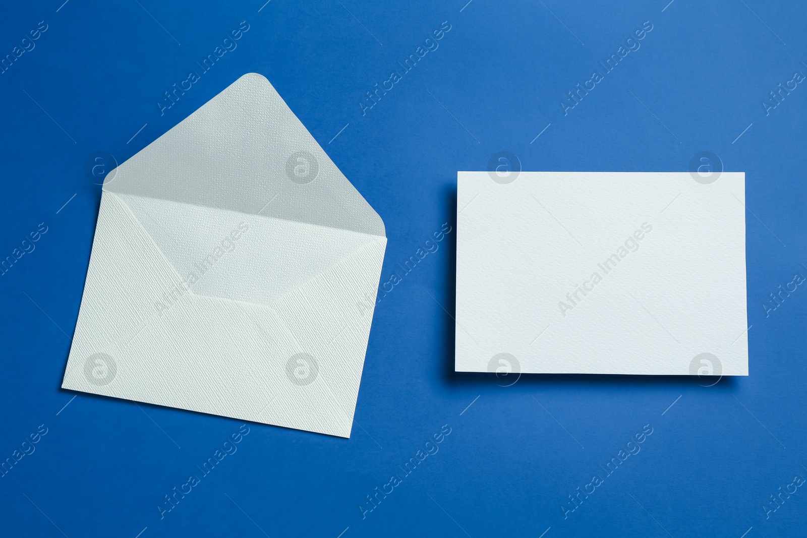 Blank invitation card and envelope on blue background, flat lay. Space for design Photo of Blank invitation card and envelope on blue background, flat lay. Space for design