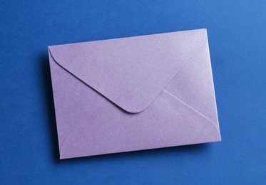 Photo of Beautiful invitation envelope on blue background, top view