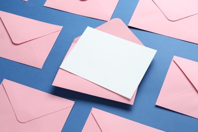 Photo of Blank invitation card and envelopes on blue background, above view. Space for design