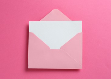 Photo of Blank invitation card and envelope on pink background, top view