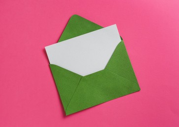 Photo of Blank invitation card and envelope on pink background, top view. Space for design