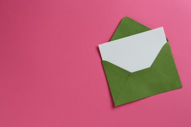 Photo of Blank invitation card and envelope on pink background, top view. Space for text