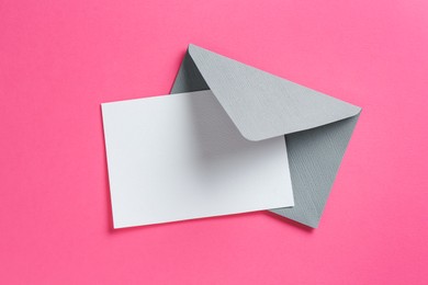 Photo of Blank invitation card and envelope on pink background, top view. Space for design