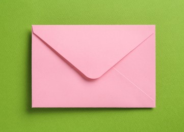 Photo of Beautiful invitation envelope on green background, top view