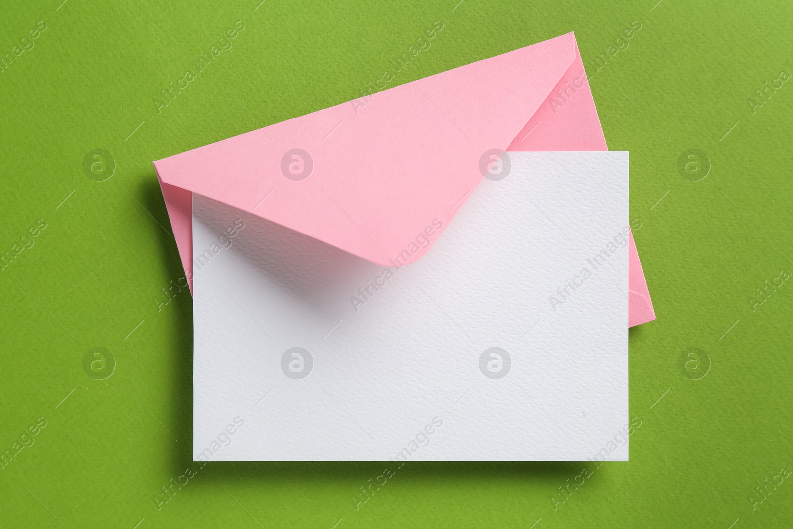 Blank invitation card and envelope on green background, top view. Space for design Photo of Blank invitation card and envelope on green background, top view. Space for design