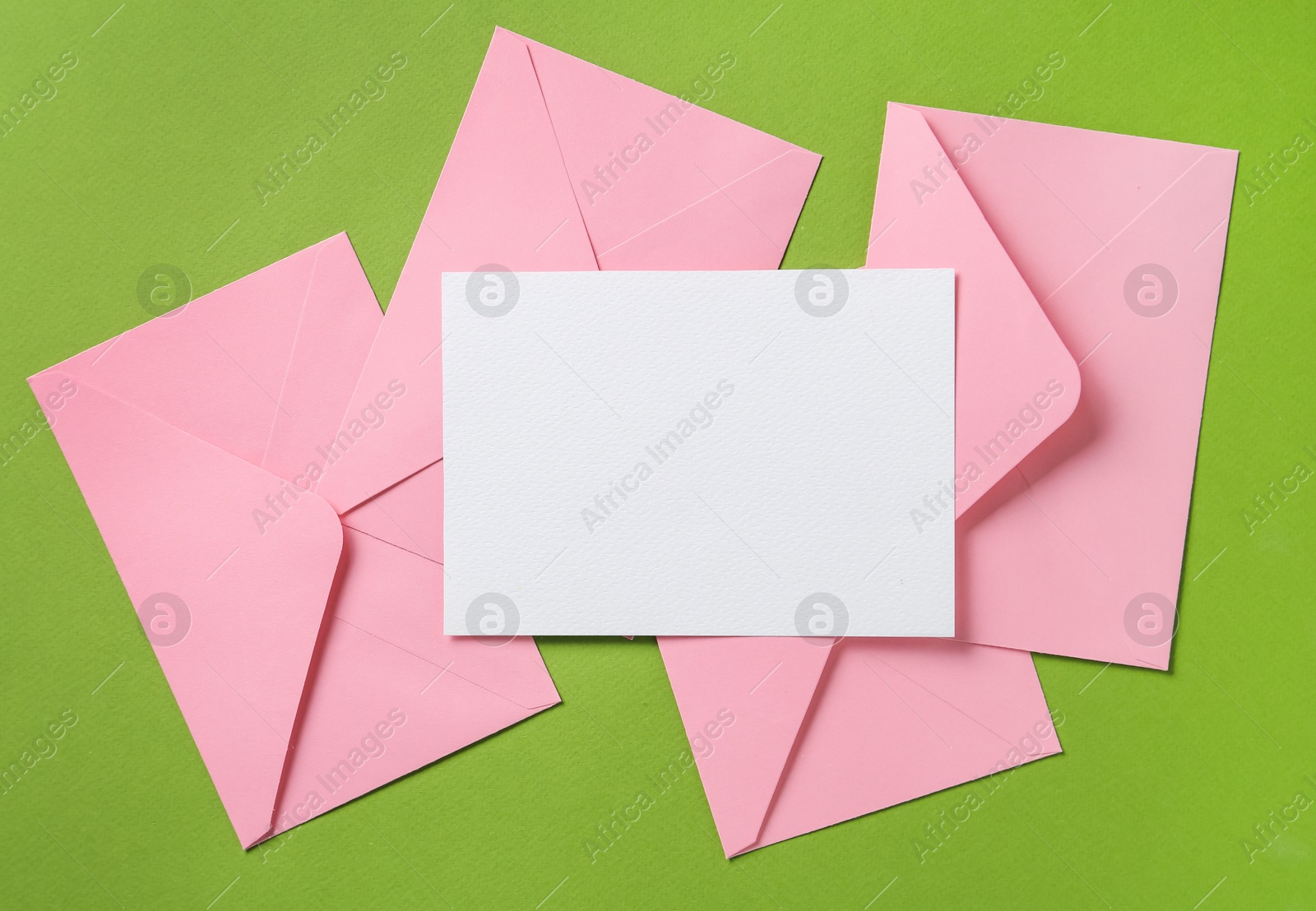 Blank invitation card and envelopes on green background, flat lay. Space for design Photo of Blank invitation card and envelopes on green background, flat lay. Space for design