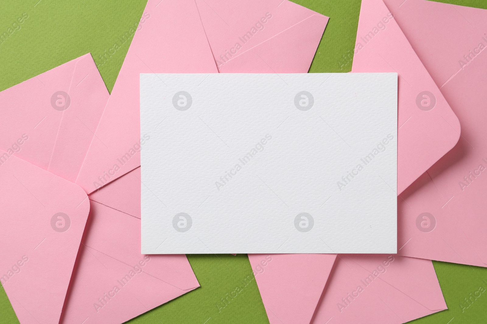 Blank invitation card and envelopes on green background, flat lay. Space for design Photo of Blank invitation card and envelopes on green background, flat lay. Space for design