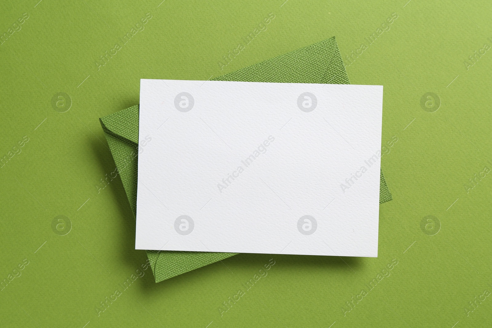 Blank invitation card and envelope on green background, top view. Space for design Photo of Blank invitation card and envelope on green background, top view. Space for design