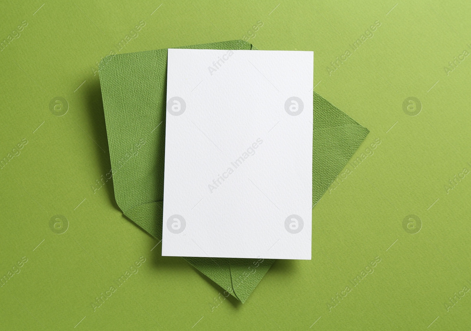 Blank invitation card and envelope on green background, top view. Space for design Photo of Blank invitation card and envelope on green background, top view. Space for design