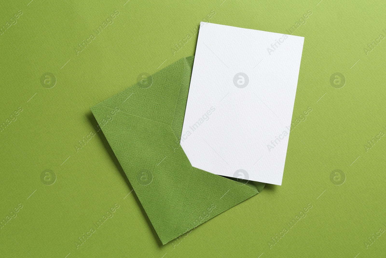 Blank invitation card and envelope on green background, top view. Space for design Photo of Blank invitation card and envelope on green background, top view. Space for design