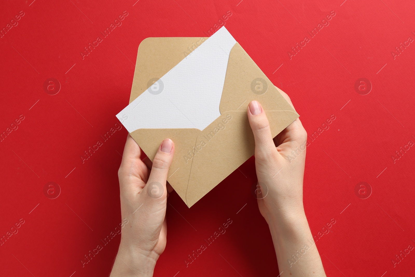 Woman holding envelope with blank invitation card on red background, top view Photo of Woman holding envelope with blank invitation card on red background, top view
