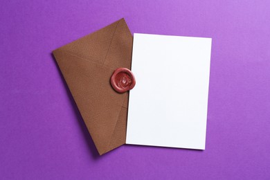 Photo of Blank invitation card and envelope on purple background, top view. Space for design