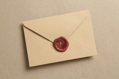 Photo of Beautiful invitation envelope with wax seal on carton, top view