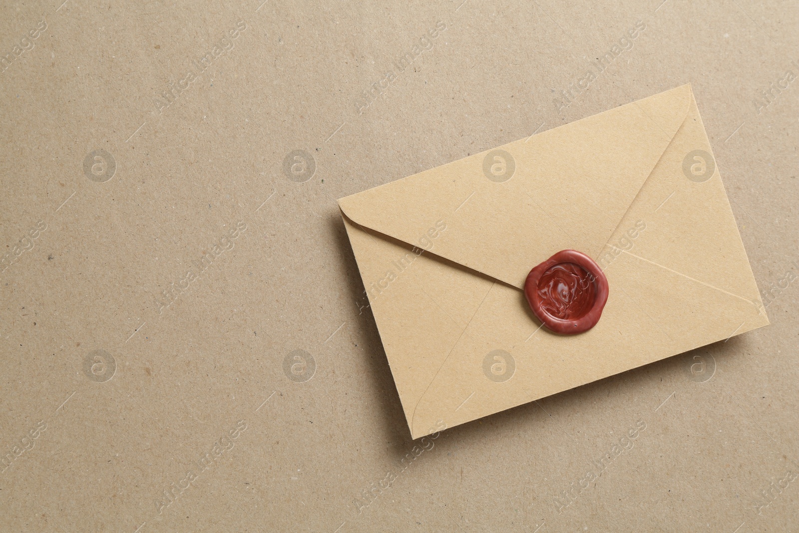 Beautiful invitation envelope with wax seal on carton, top view. Space for text Photo of Beautiful invitation envelope with wax seal on carton, top view. Space for text