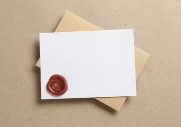 Photo of Blank invitation card with wax seal and envelope on carton, top view. Space for design