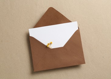 Photo of Blank invitation card with flowers and envelope on carton, top view
