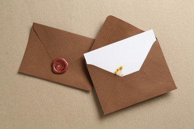 Photo of Blank invitation card with flowers and envelopes on carton, flat lay