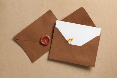 Photo of Blank invitation card with flowers and envelopes on carton, flat lay