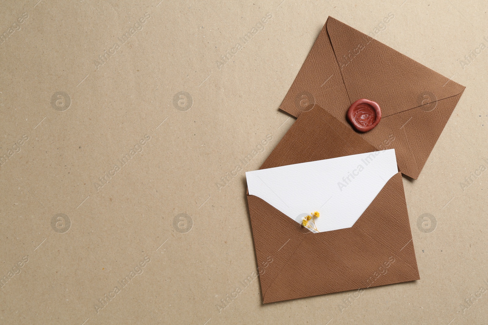 Blank invitation card with flowers and envelopes on carton, flat lay. Space for text Photo of Blank invitation card with flowers and envelopes on carton, flat lay. Space for text