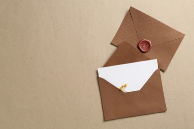 Photo of Blank invitation card with flowers and envelopes on carton, flat lay. Space for text