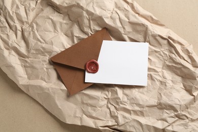 Photo of Blank invitation card, envelope and parchment paper on carton, top view. Space for design