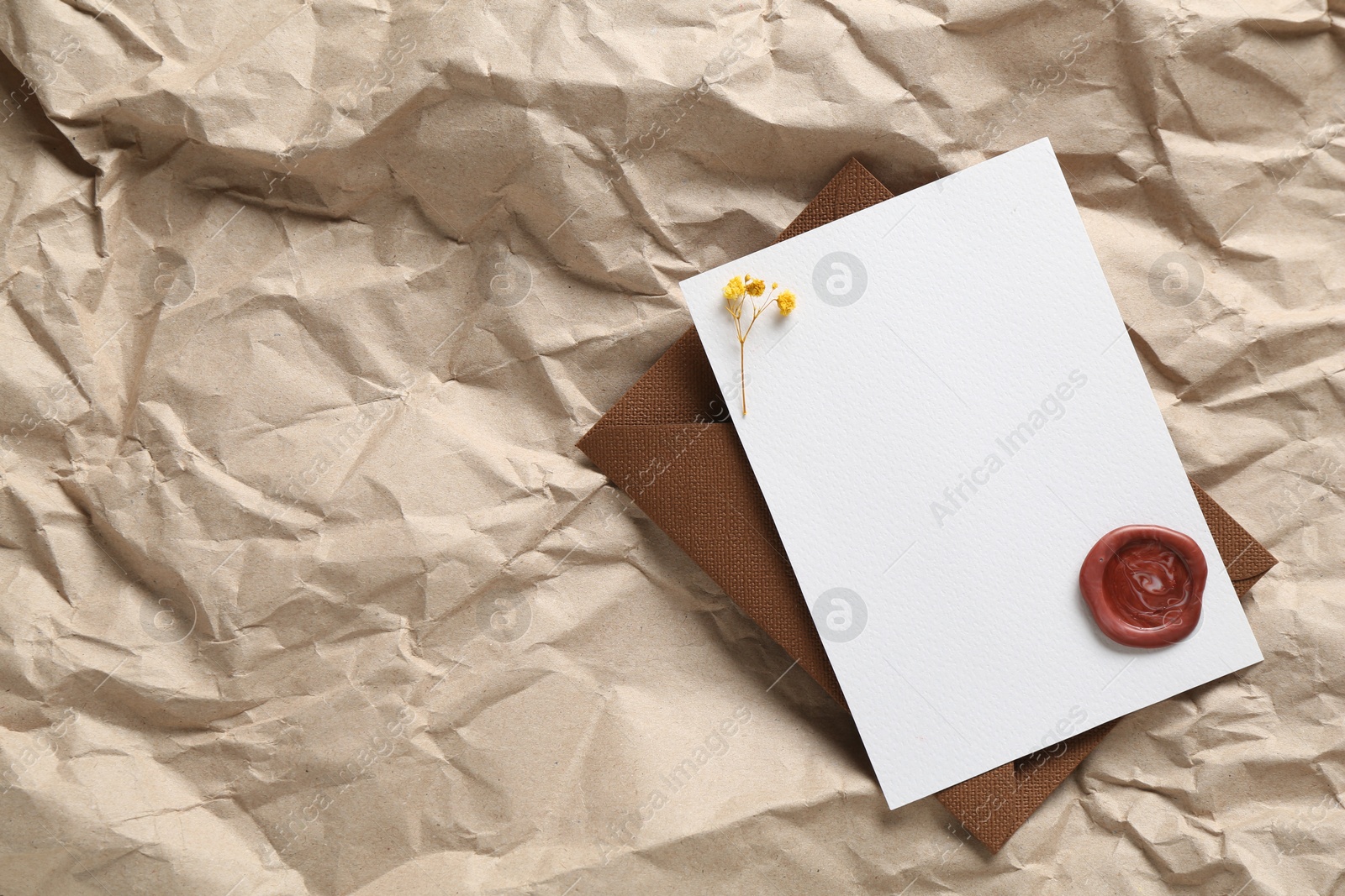 Blank invitation card with flowers, wax seal and envelope on parchment paper, top view. Space for design Photo of Blank invitation card with flowers, wax seal and envelope on parchment paper, top view. Space for design
