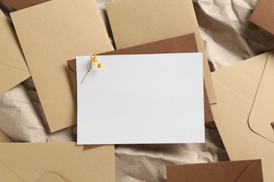 Photo of Blank invitation card with flowers and envelopes on parchment paper, flat lay. Space for design