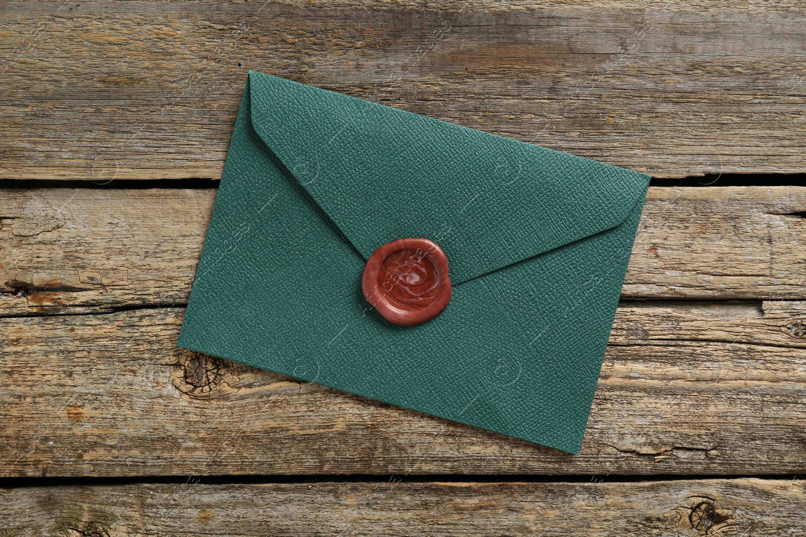 Beautiful invitation envelope with wax seal on wooden table, top view Photo of Beautiful invitation envelope with wax seal on wooden table, top view