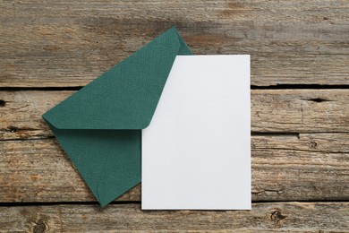 Photo of Blank invitation card and envelope on wooden table, top view. Space for design
