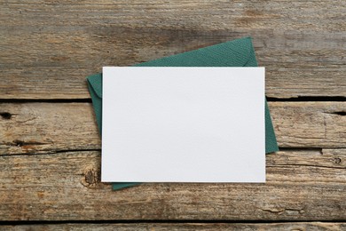Photo of Blank invitation card and envelope on wooden table, top view. Space for design
