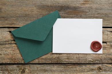 Photo of Blank invitation card and envelope on wooden table, top view. Space for design