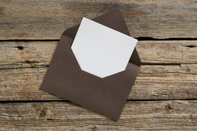 Photo of Blank invitation card and envelope on wooden table, top view. Space for design