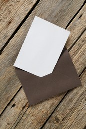 Photo of Blank invitation card and envelope on wooden table, top view. Space for design