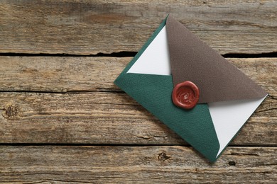 Photo of Blank invitation card and envelopes on wooden table, top view. Space for text