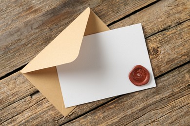 Photo of Blank invitation card with wax seal and envelope on wooden table, top view. Space for design