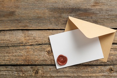 Photo of Blank invitation card with wax seal and envelope on wooden table, top view. Space for design