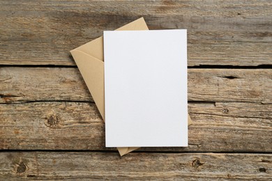 Photo of Blank invitation card and envelope on wooden table, top view. Space for design