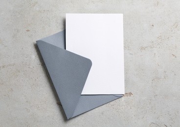 Photo of Blank invitation card and envelope on light grey table, top view. Space for design