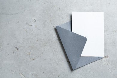 Photo of Blank invitation card and envelope on light grey table, top view. Space for design
