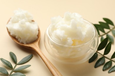 Photo of Shea butter and leaves on beige background, closeup