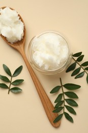 Photo of Shea butter and leaves on beige background, flat lay