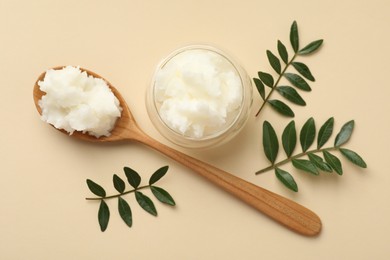 Photo of Shea butter and leaves on beige background, flat lay