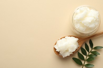 Photo of Shea butter and leaves on beige background, flat lay. Space for text