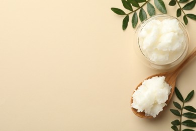 Photo of Shea butter and leaves on beige background, flat lay. Space for text
