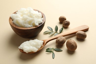 Photo of She butter, nuts and leaves on beige background, closeup