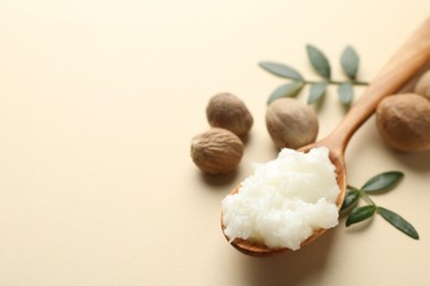 Photo of She butter, nuts and leaves on beige background, closeup. Space for text