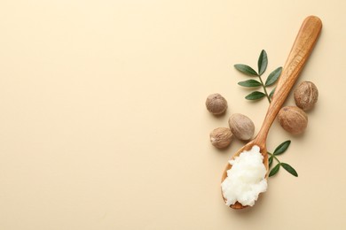 Photo of She butter, nuts and leaves on beige background, flat lay. Space for text